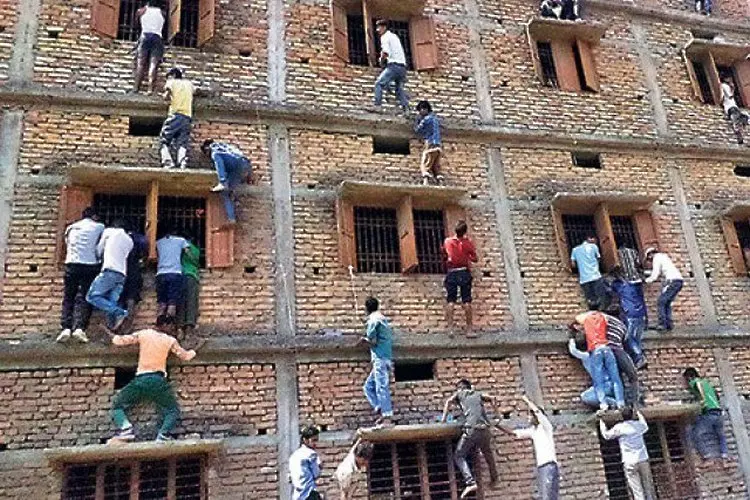 Индия: Родители висят по стените на училище, за да подсказват на изпит