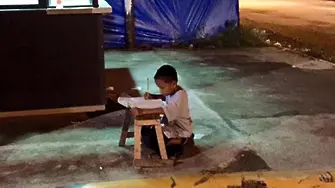 9-годишен бездомник пише домашни на улично осветление